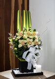 Arreglo floral con orquídeas y velón